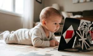 Newborn doing tummy time looking at high-contrast black and white toys for visual development.