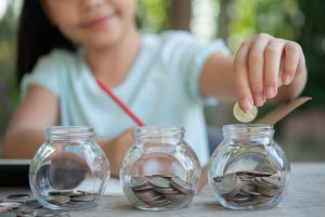 Child filling clear savings jar teaching kids money saving basics