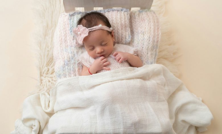 Newborn baby sleeping peacefully in white crib — newborn sleep schedule guide
