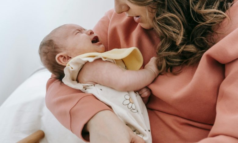 Exhausted mother in a dark nursery holding her awake 6-month-old won't sleep unless held.
