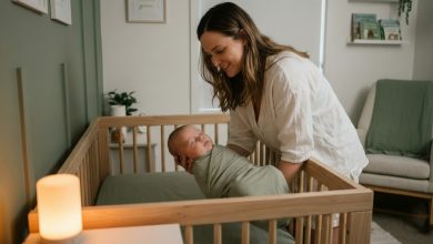 An exhausted but relieved mom successfully learning how to transfer sleeping baby to crib without waking them in a cozy nursery.