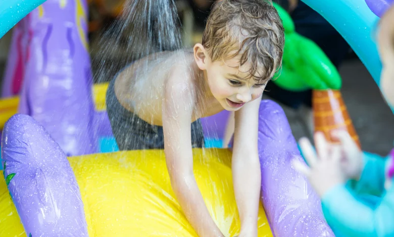 Toddler playing with inexpensive water play for toddler in backyard