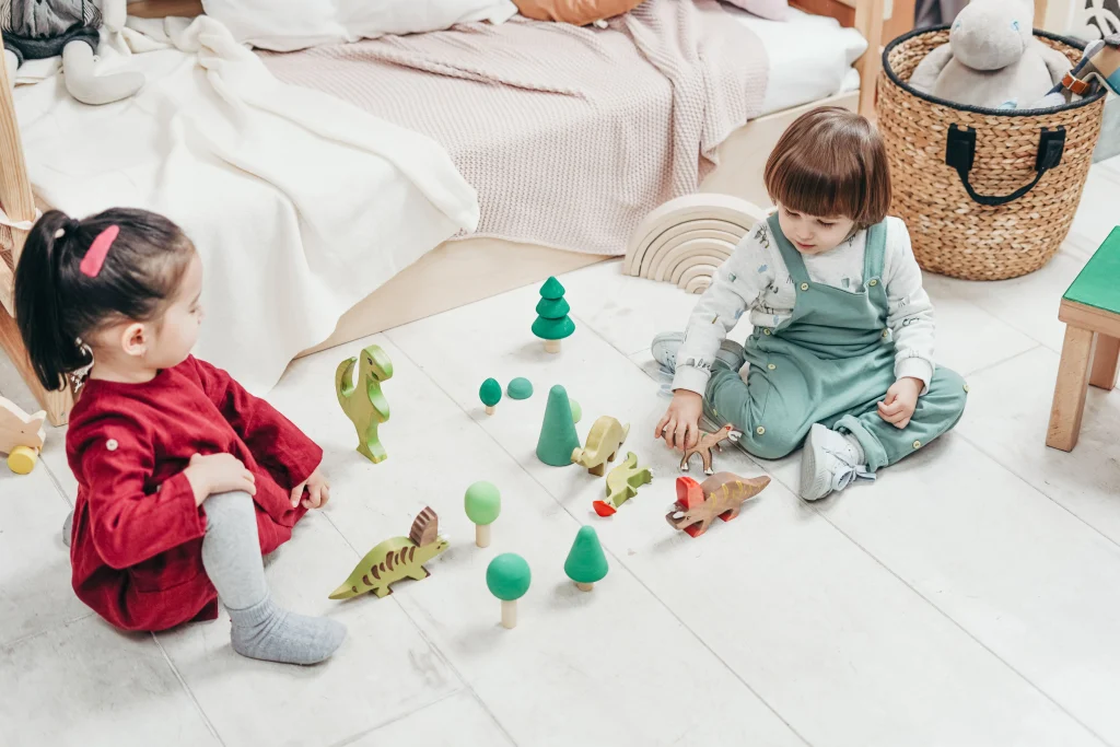 toddler putting toys into a storage basket with help from a parent