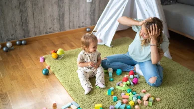 toddler playing with blocks while mother looks on in a relatable parenting moment