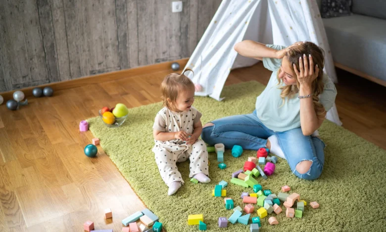 toddler playing with blocks while mother looks on in a relatable parenting moment